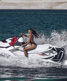 a woman riding on the back of a white and black jet ski