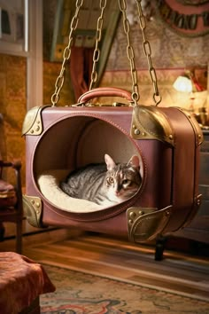 a cat laying in a brown suitcase hanging from a metal chain on a chair with a lamp behind it