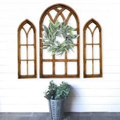 a potted plant sitting in front of two arched windows on the side of a wall