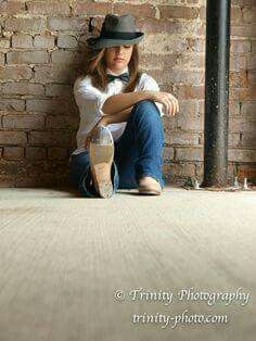 a woman sitting on the floor with her legs crossed and wearing a hat, jeans and heels