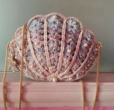 a crocheted purse sitting on top of a window sill next to a chain