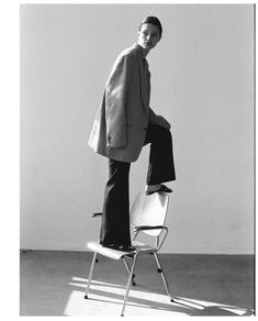 a black and white photo of a man standing on a chair