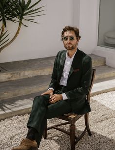 a man sitting on top of a wooden chair next to a potted palm tree