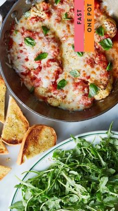 a pizza in a pan on top of a table next to some bread and salad