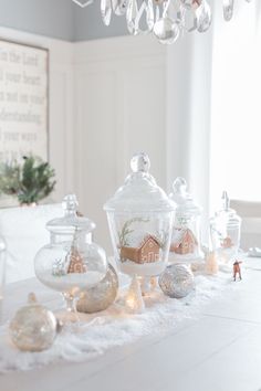 a white table topped with christmas ornaments and glass jars filled with candy ornament