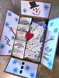 an open box filled with marshmallows on top of a table next to snowflakes