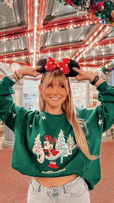 a woman wearing mickey mouse ears with christmas lights in the background