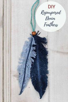 a feather ornament hanging from a string on a white wooden background with a tag that says repraposed denim feathers