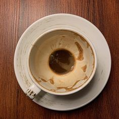 a white bowl filled with brown liquid on top of a wooden table