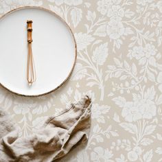 a white plate topped with a metal whisk on top of a table