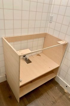 a wooden cabinet sitting on top of a hard wood floor next to a white tiled wall