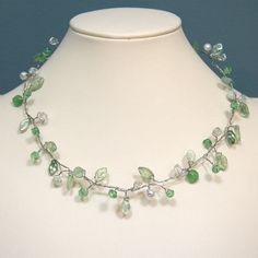 This necklace is made from a mixture of glass, imitation pearl, Czech glass, and glass leaf beads.  Strung and twisted on silvery wire, they resemble leaves on a branch.  This necklace is very light and comfortable to wear (despite its looks), and can be bent into whatever shape you like.  Being more three dimensional than many necklaces also adds interest.  This necklace is 18.5 inches long, with a lobster-claw clasp.  The length can be altered upon request.  It will be flattened somewhat for s Affordable Green Elegant Pearl Necklace, Cheap Green Beaded Pearl Necklace, Cheap Green Glass Beaded Necklaces, Czech Glass Necklace, Leaf Beads, Branch Necklace, Green Beaded Necklace, Peridot Green, Green Necklace