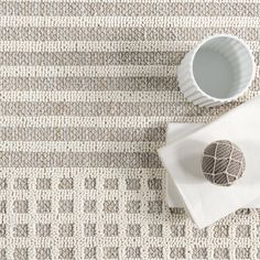 a table topped with a white plate next to a cup and saucer on top of a rug