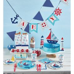 a table topped with plates and cups filled with cake next to an ocean themed banner