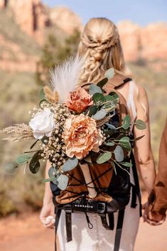 a bride and groom hold hands as they walk through the desert