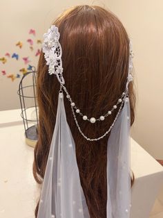 the back of a woman's head wearing a veil with pearls