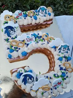 a cake shaped like the letter e is decorated with blue and white frosting, along with an image of sonic