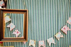 a photo frame hanging on the wall next to a striped table cloth with paper hearts