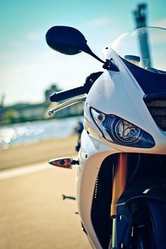 the front end of a motorcycle parked on the side of the road next to water