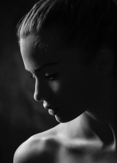 a black and white photo of a woman's face with her hair pulled back