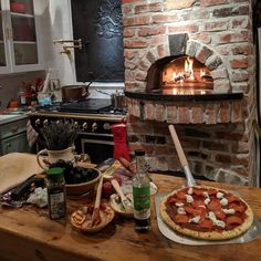 a pizza sitting on top of a wooden table next to a brick oven with an open door