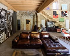 a living room filled with lots of furniture and paintings on the wall next to stairs