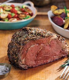 a piece of meat sitting on top of a wooden cutting board next to other foods