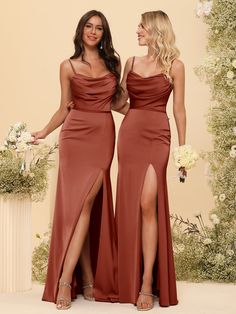 two women standing next to each other in long dresses with slits on the legs