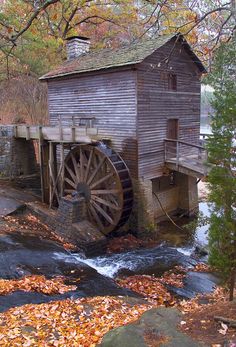 a water mill in the fall with leaves on the ground