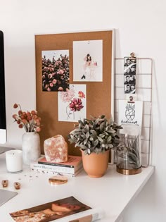 a white desk topped with plants and pictures