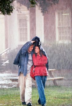 two people walking in the rain under an umbrella