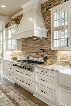 a kitchen with white cabinets and an oven in the center, along with a brick wall