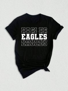 Introducing our Team Mascot Shirt, a must-have for all proud Eagles!  Show off your team spirit and pride with this Eagles School Shirt, designed to celebrate your love for the Eagles and their glorious mascot. This Eagles Mascot Tee is perfect for game days, pep rallies, or simply to represent your team wherever you go. Crafted with premium quality materials, this Eagles Pride Shirt ensures comfort and durability. The soft fabric keeps you feeling cozy, while the vibrant design showcases your l College Fan Apparel T-shirt With Team Name, Game Day Black Tops With Team Name, Black Tops With Team Name For Game Day, Sports Fan Graphic Print T-shirt For College, Black Tops With Text Print For Football Season, Collegiate T-shirt With Name Print For Fans, Team Spirit T-shirt With Letter Print For Fans, Black Tops For Game Day With School Spirit, Graphic Tee With Team Logo For Football Season