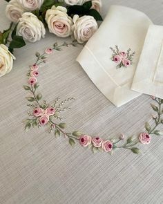 some white and pink roses are on a table with two napkins in front of them