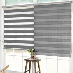 a living room with a large window covered in shades of grey and white striped blinds