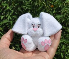 a small white stuffed elephant sitting on top of someone's hand