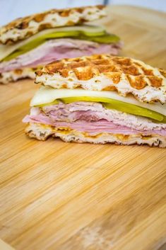 a sandwich cut in half sitting on top of a wooden cutting board