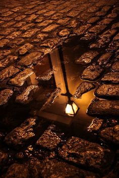 a street light sitting on top of a cobblestone road with arabic writing above it