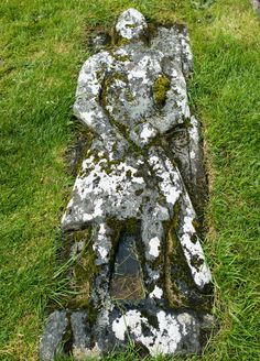 a stone bench with moss growing on it's sides in the middle of a grassy area