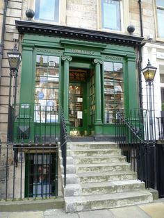 a green door is on the side of a building with stairs leading up to it