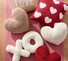 valentine's day pillows and decorations on a pink surface with the word love spelled out