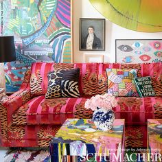 a living room filled with lots of colorful furniture and paintings on the wall behind it