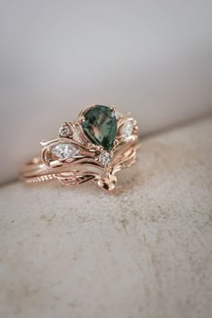 a green and white diamond ring sitting on top of a table