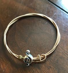 a close up of a metal bracelet on a wooden table with a beaded clasp