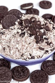 oreo cookies and cream in a blue bowl surrounded by chocolate chips on a white surface