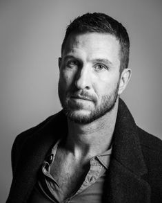 a black and white photo of a man in a jacket looking at the camera with a serious look on his face