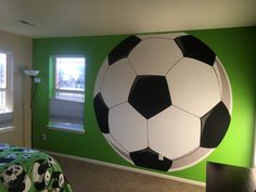 a large soccer ball painted on the wall in a child's bedroom with green walls