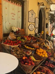 many baskets of fruit are on display in front of a storefront with an arched window