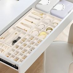 a white desk with drawers filled with jewelry and bracelets on it's sides