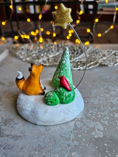 a small christmas tree on top of a rock with a fox figurine next to it